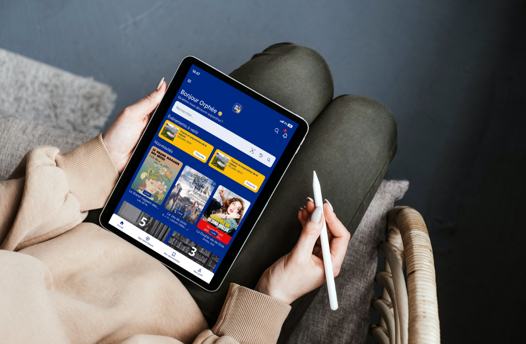 Personne qui tient une tablette avec l'application "Ma Bibli"