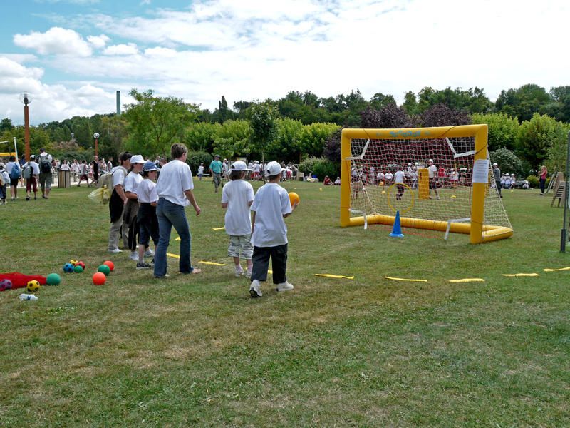 Des enfants en train de tirer dans des cages de foot avec des plots autour