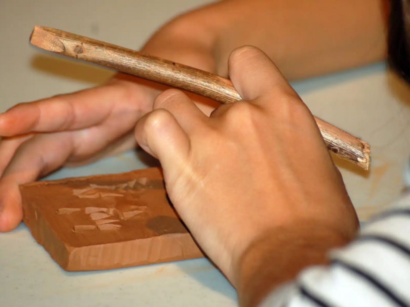 Mains écrivant sur une tablette d'argile avec un bâtonnet